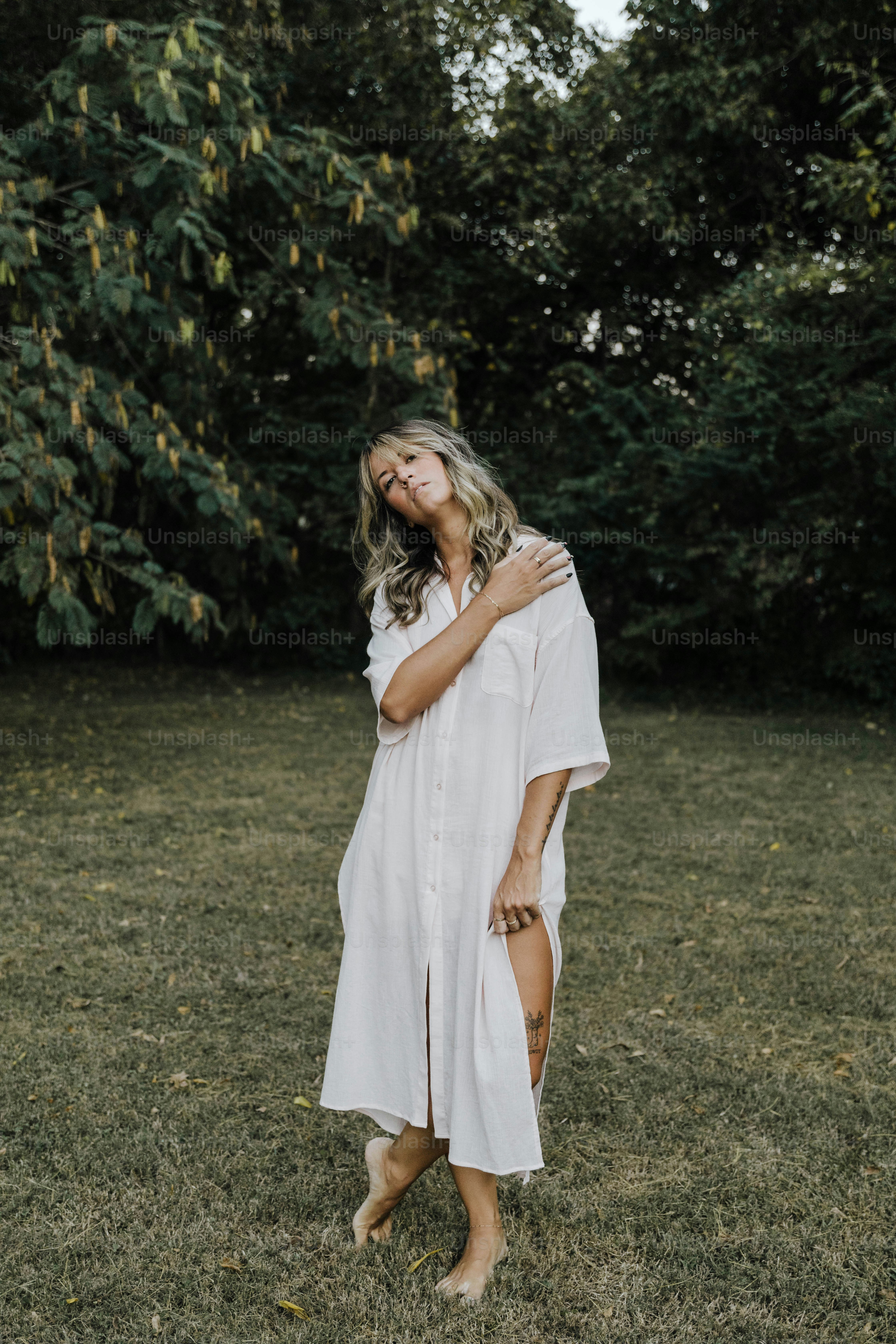 a woman in a white dress standing in a field