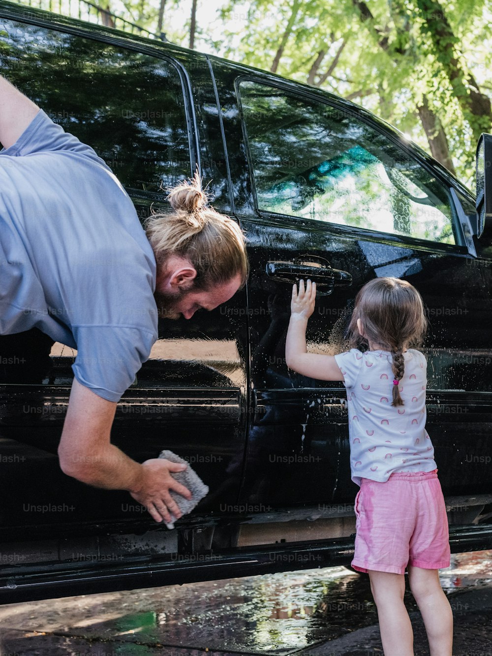 a man helping a little girl get out of a black van
