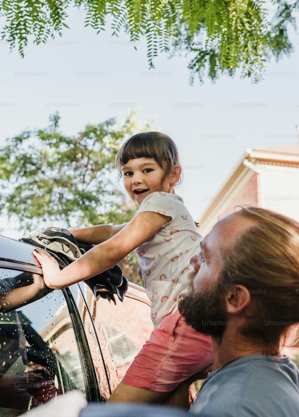 a man holding a little girl on top of a car