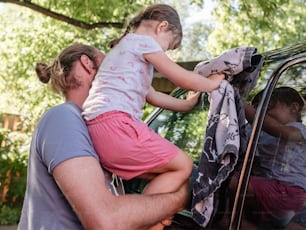 a man and a little girl hanging out of a car window