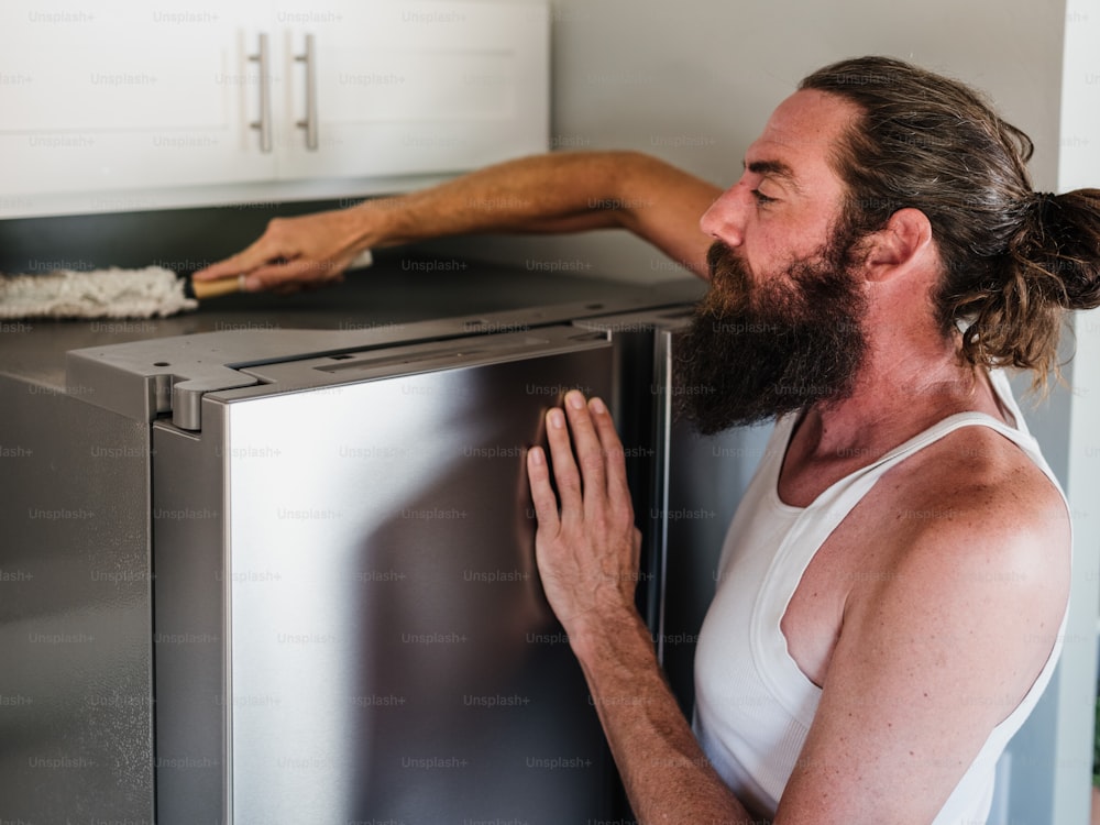 a man with a beard is leaning on a refrigerator