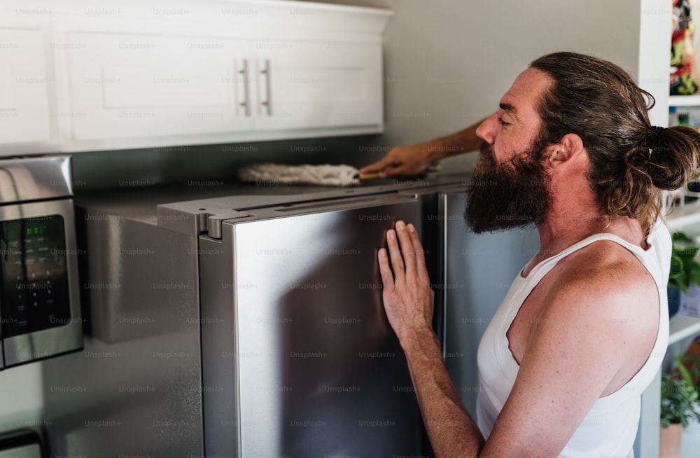 a man with a beard standing next to a refrigerator