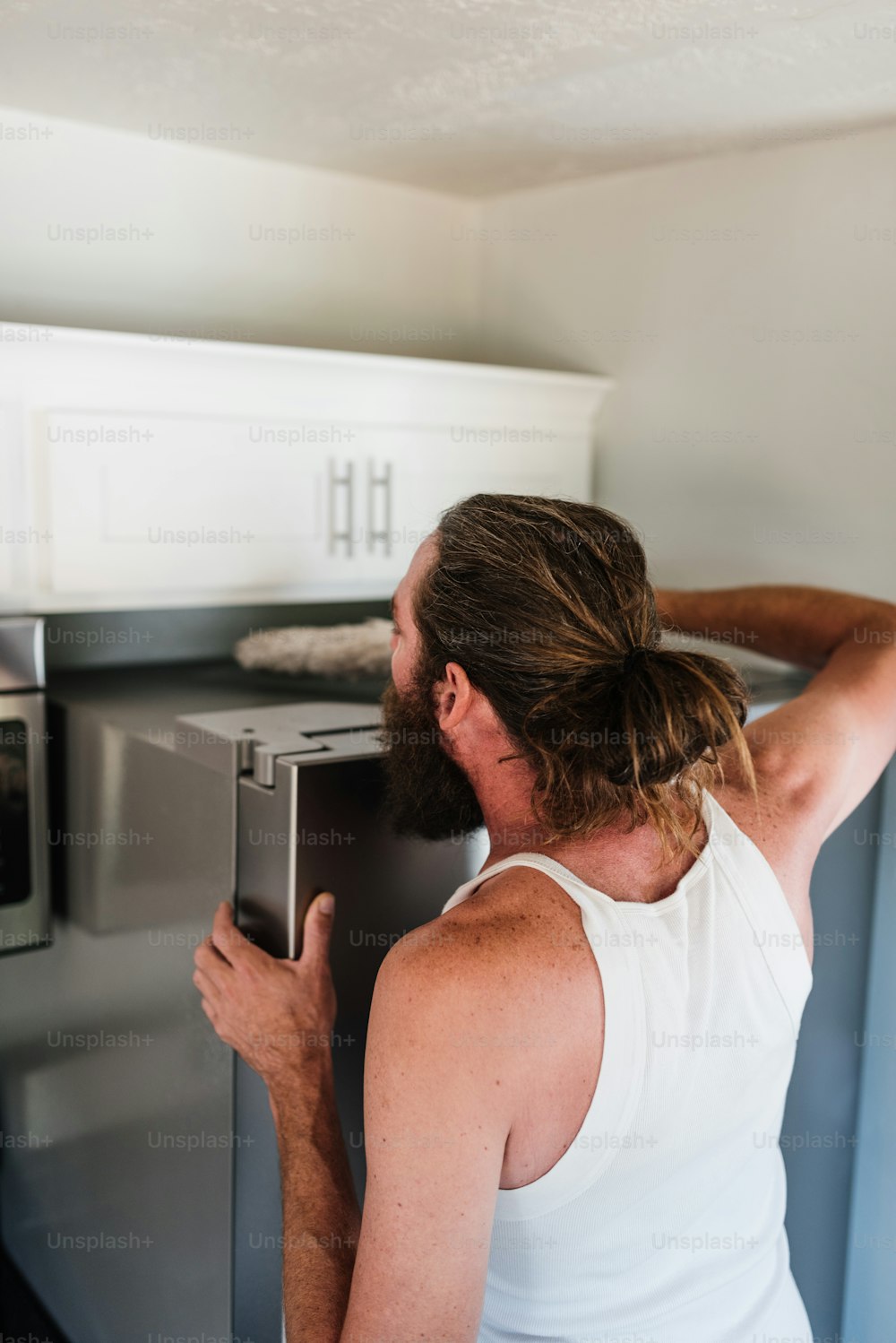 a man with a beard is looking into a microwave