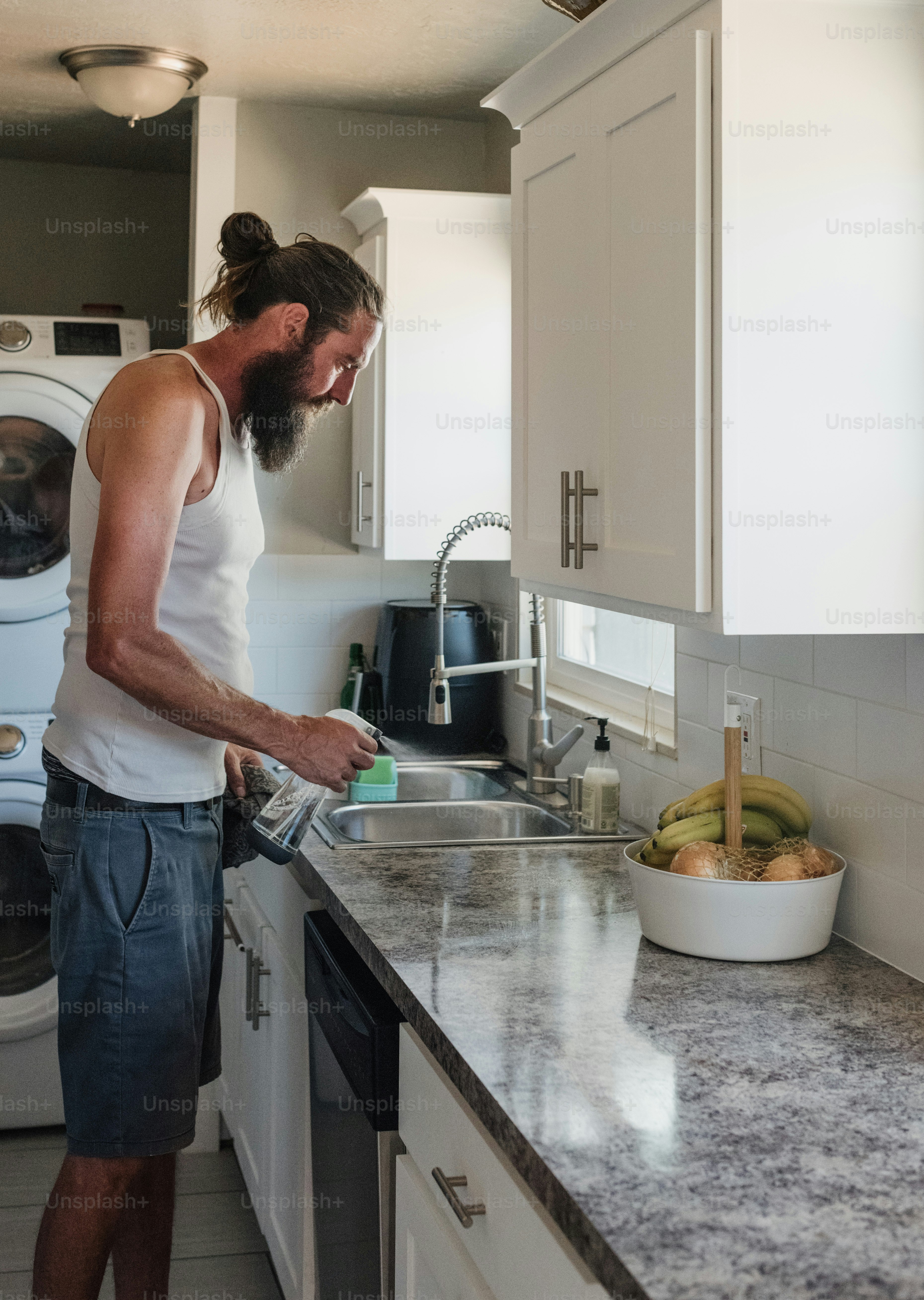 a man standing in a kitchen next to a sink