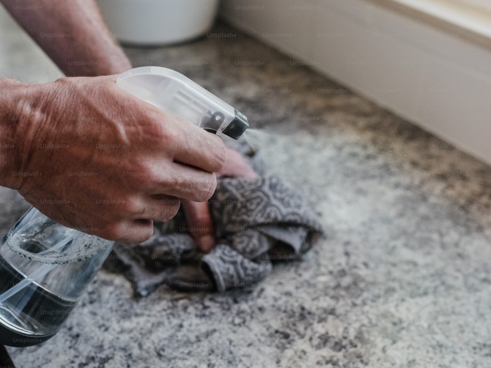 a person holding a cloth and a blender on a counter