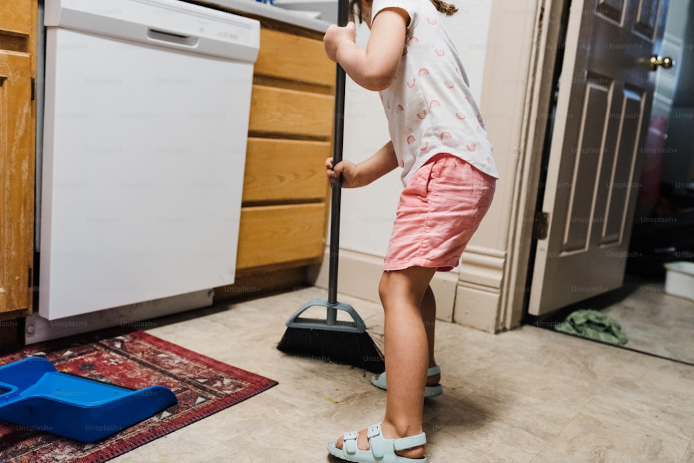 Una bambina che pulisce il pavimento con una scopa