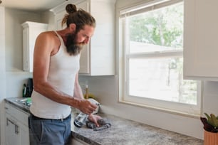 a man in a white tank top standing in a kitchen