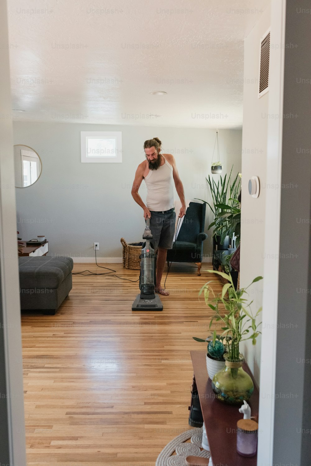 um homem aspirando um piso de madeira dura em uma sala de estar