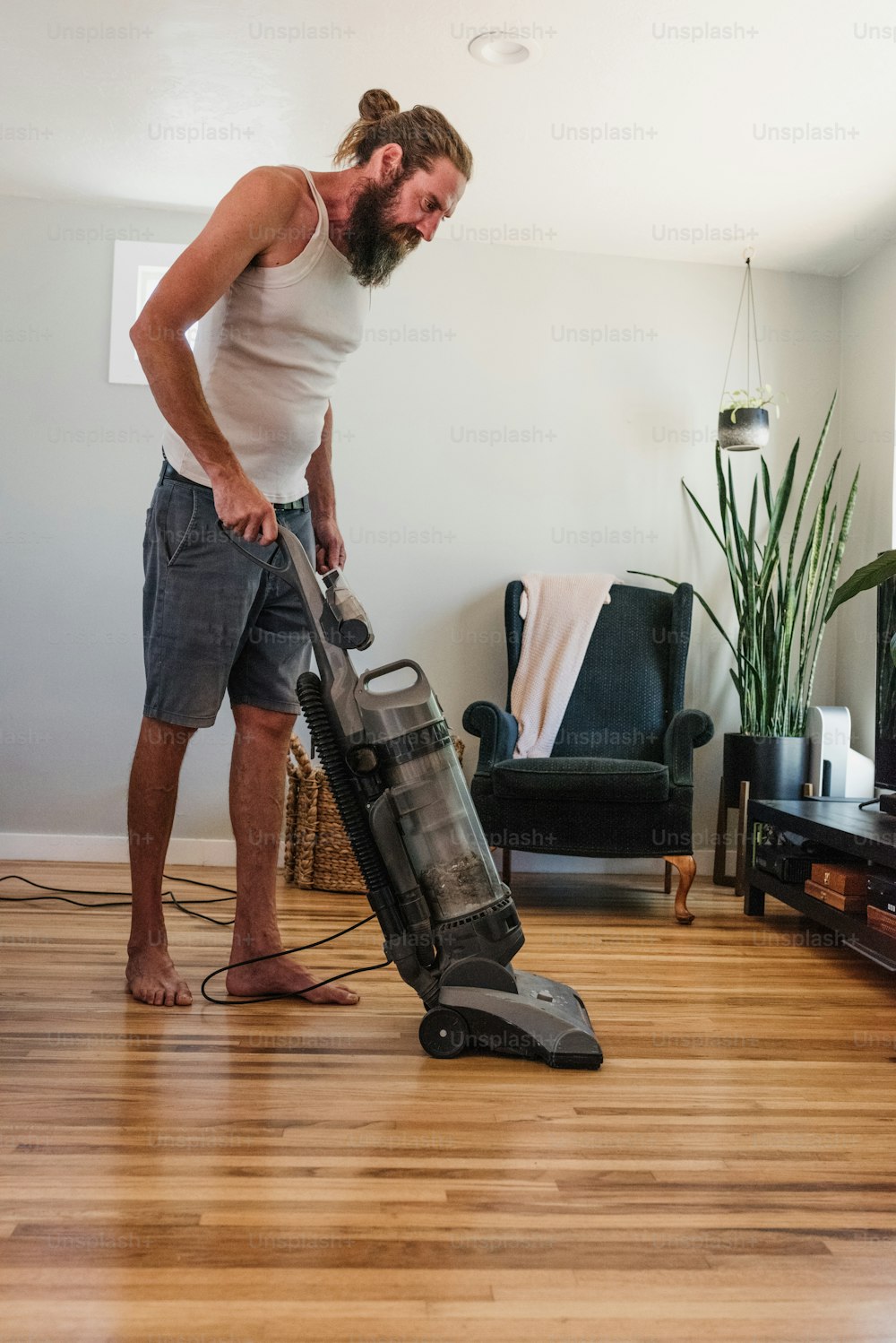 a man standing on a hard wood floor with a vacuum