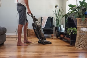 Un hombre usando una aspiradora para limpiar un piso de madera