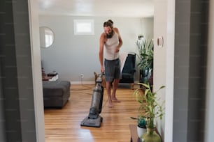 a man standing in a living room with a vacuum