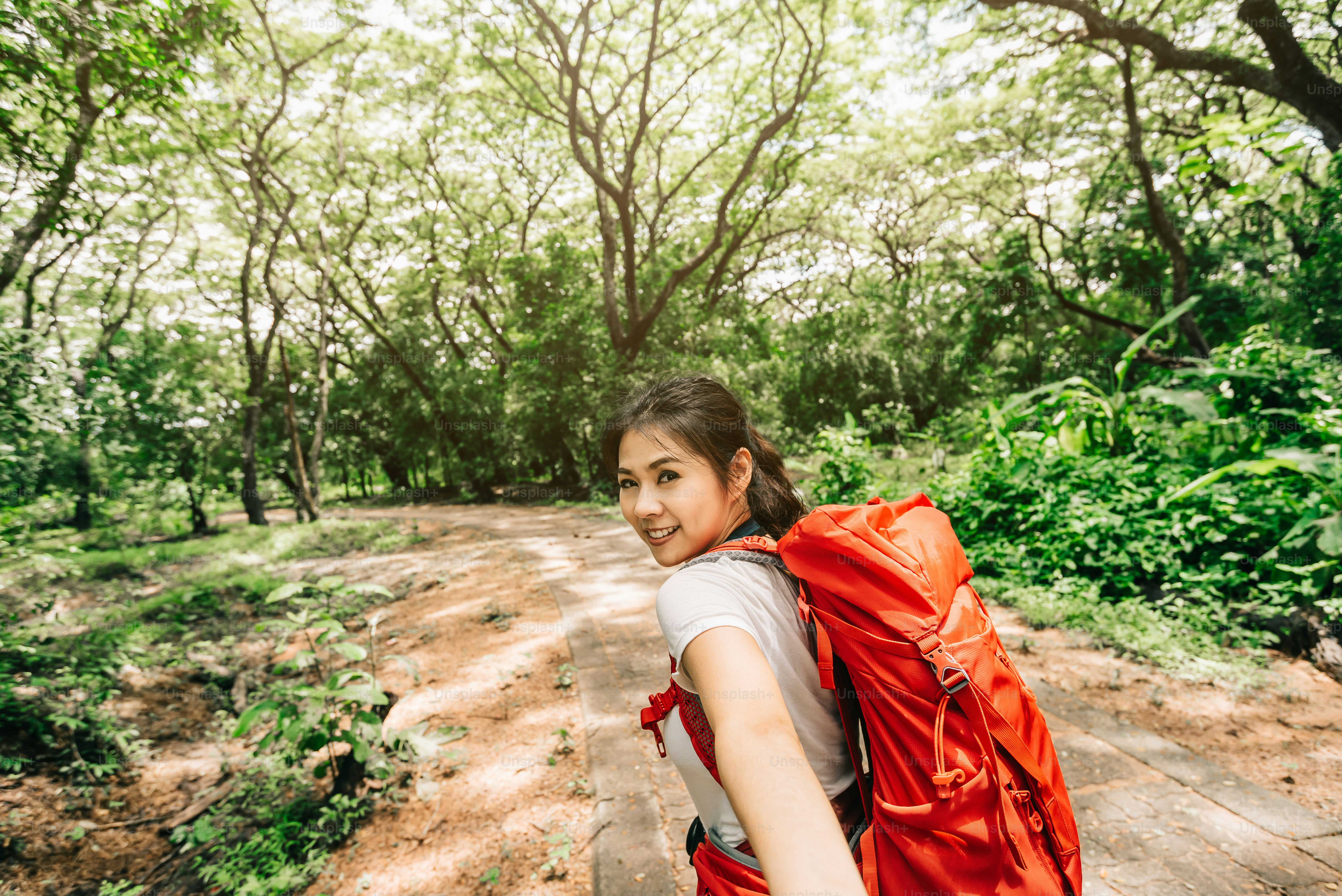 Happy smile young beautiful Asian woman leading you into forest for traveling