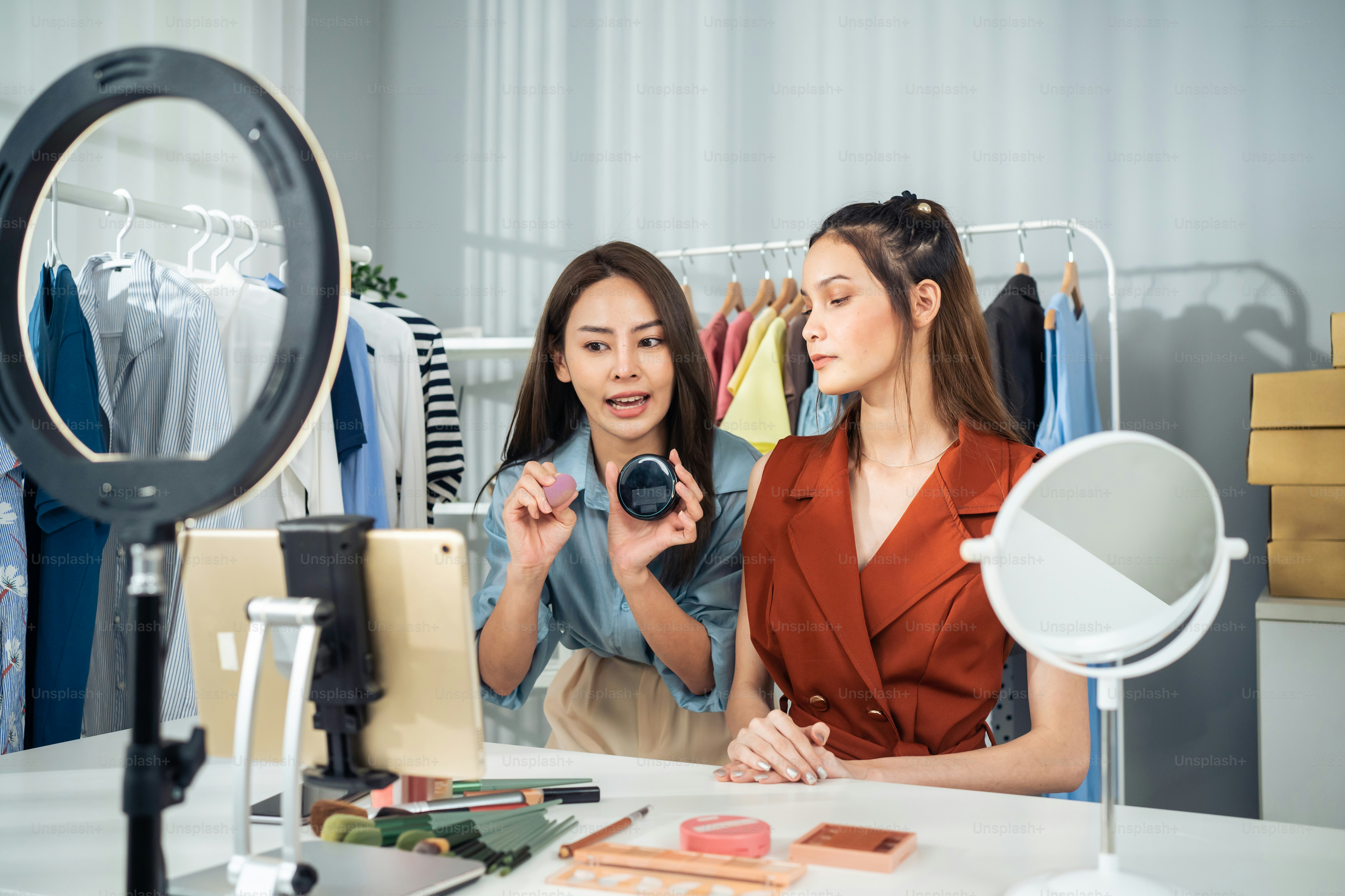 Asiatische zwei Frauen Vlogger sprechen mit der Kamera, um die Kosmetik zu Hause zu überprüfen. Schöne Beauty-Bloggerin Influencer Freundinnen Paare Live-Streaming und zeigen Make-up-Pinsel für Follower im Büroladen.
