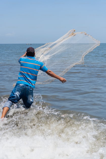 Fisher on the beach casting a fishing net photo – Fishing net