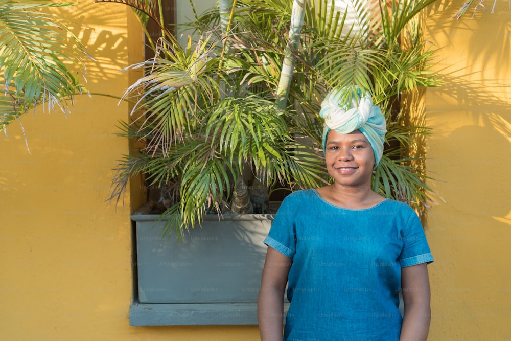 Retrato de uma mulher africana com uma cobertura de cabeça tradicional colorida ao ar livre.
