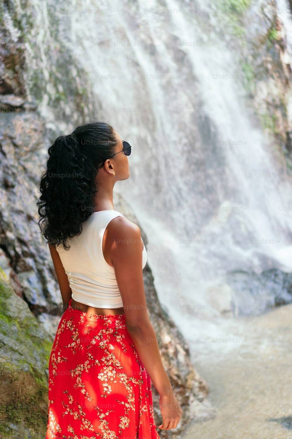 Schöne junge Frau am Fuße eines tropischen Wasserfalls. Urlaubskonzept