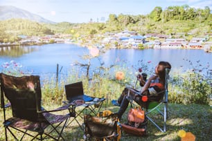 Asian female tourists camping and And working notebook, She is happy, relaxed, enjoying reading a book.