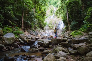 Asiatische Frauen entspannen sich im Urlaub. Reisewasserfall Auf dem Berg (Huai Toh Wasserfall) in Krabi. Reisen Sie in die Natur, Reisen Sie entspannen, Wald wandern, Reisen Thailand.