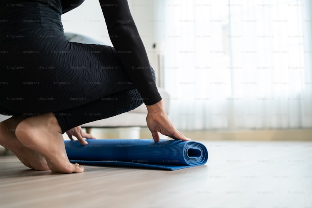 Focused senior woman doing yoga at home. 70 years old woman sitting on  fitness mat with outstretched hands resting on her knees performing yoga in  living room. stock photo - OFFSET