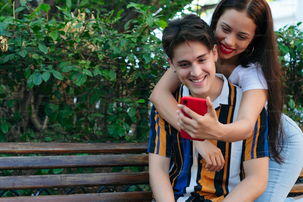 Happy young man with girlfriend taking a selfie at park