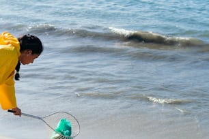 Jovem ambientalista recolhendo plásticos por praia