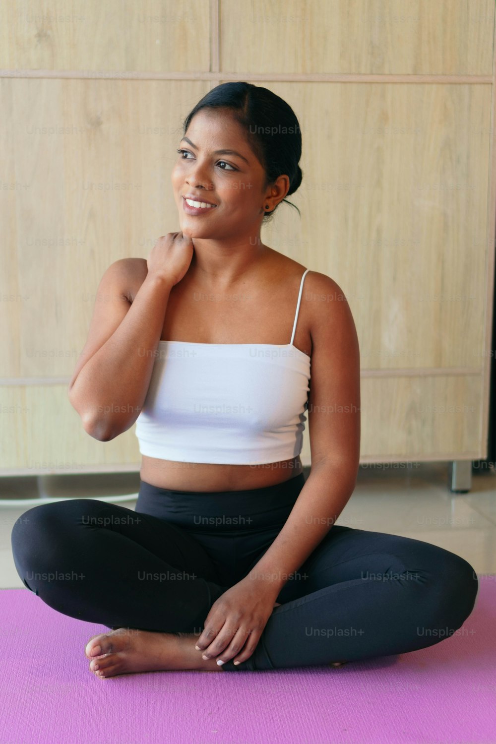 Black Woman practicing yoga, exercising, wearing sportswear, black pants and top.