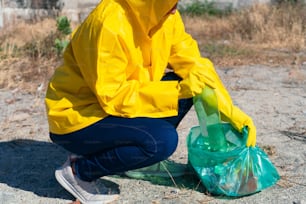 Middle-aged woman placing a plastic jar in a plastic bag in the park.