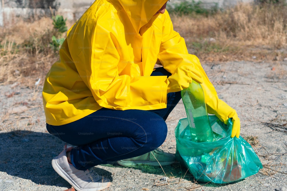 Une femme d’âge moyen place un pot en plastique dans un sac en plastique dans le parc.