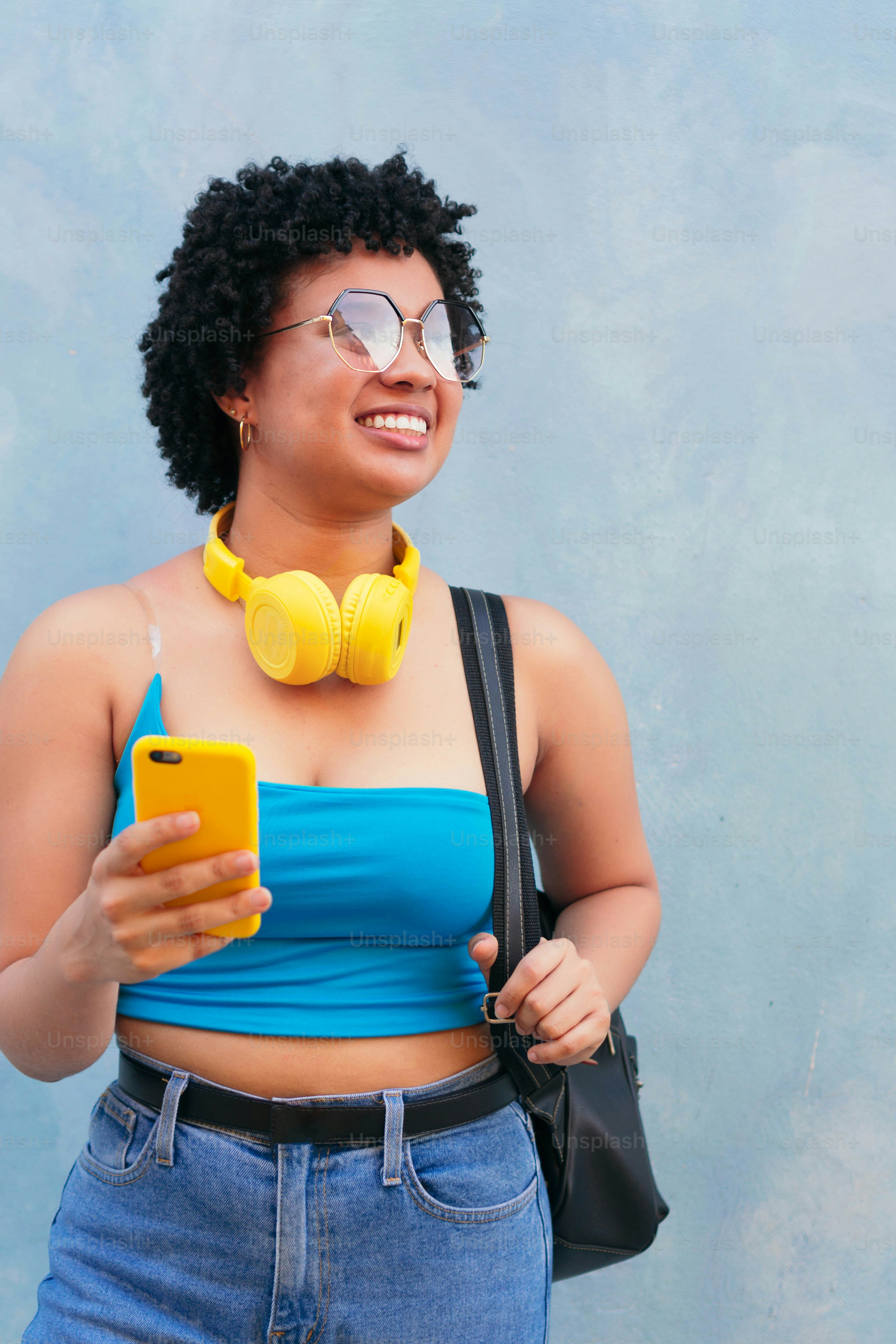 Cheerful young woman holding phone outdoors