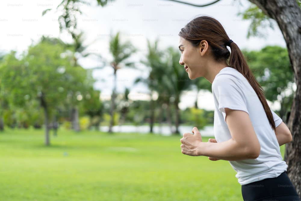 Asian young beautiful sport woman running on street in public park. Beautiful athlete fit and firm girl in sportswear exercise by jogging workout outdoor for health care in evening sunset in garden.