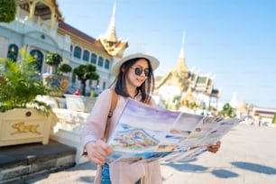 Mulher asiática feliz com um mapa guia e uma mochila que viaja na Tailândia