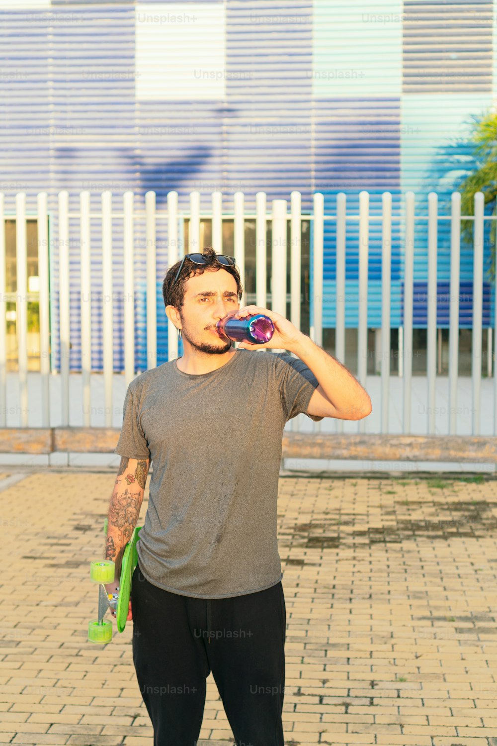 Latin man drinking water after skateboarding
