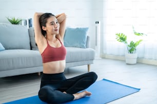 Asian young beautiful active woman doing Yoga Pilates workout at home. Attractive girl in sportswear feel happy and relax, follow exercise instruction video from online trainer in living room in house