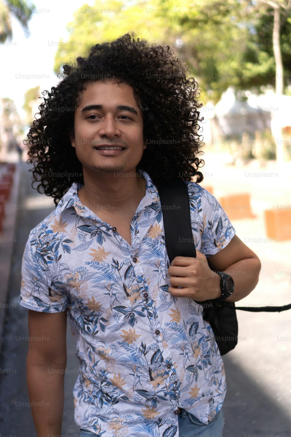 Man with afro hair, wearing a backpack, walking down the street