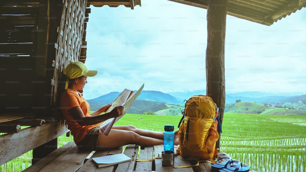 アジアの女性は自然を旅します。リラックスした旅。リゾートのバルコニーに座って地図を見てください。夏の山岳地帯の眺め。タイ