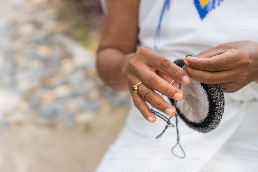 Tejedor colombiano irreconocible con vestimenta tradicional. Precioso primer plano de las manos de una mujer en la Sierra Nevada de Santa Marta haciendo productos hechos a mano.