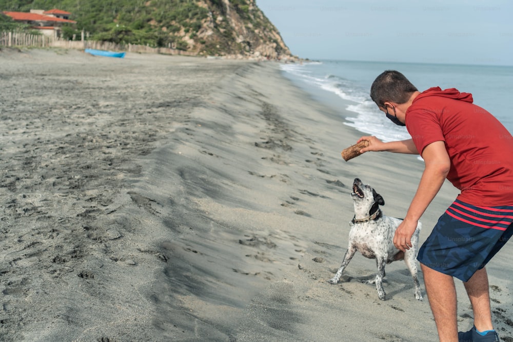 Hispanischer Mann hat Spaß mit ihrem Hund am Strand