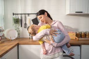 Caucasian loving mother hold baby boy toddler to lull him to sleep. Attractive mom carry little kid son with gentle and tenderness for healthy daytime nap in house. Motherhood-parenting concept.