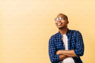 portrait of a smiling young black adult wear glasses and crossing his arms. happiness concept.