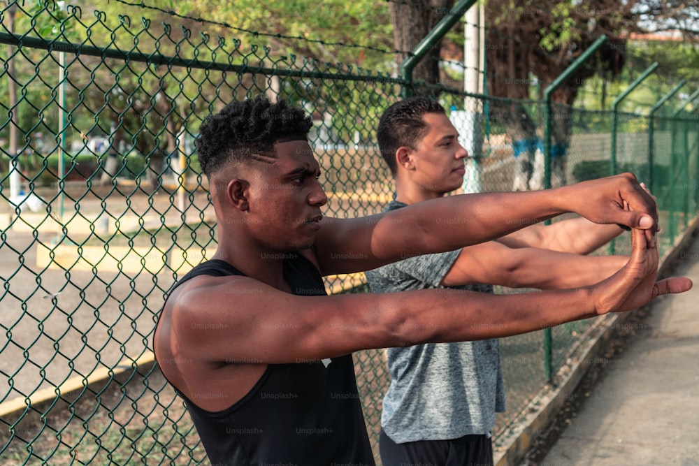 Atletas masculinos decididos haciendo ejercicios de estiramiento en el parque