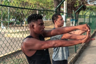 Determined male athletes doing stretching exercises on park