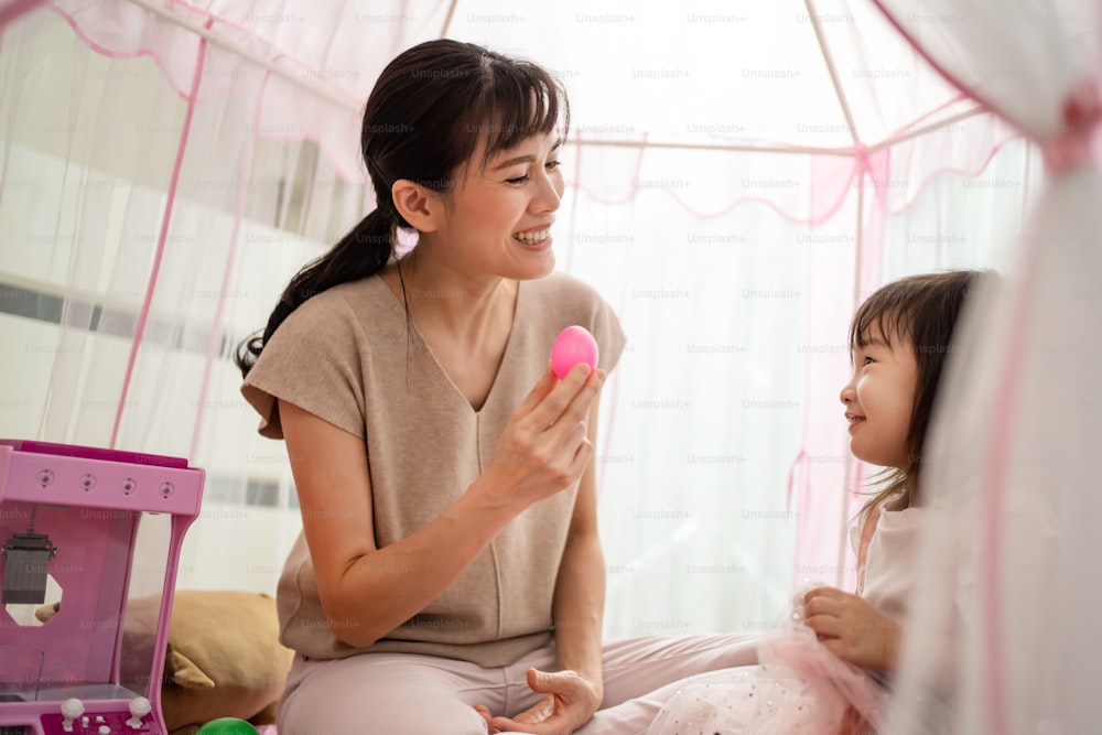 Asian mother teach young girl daughter about color in tent at home. Beautiful loving Parent play education game with little kid to learn and develop speaking skill. Parenting activity in house concept