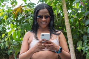 Young Afro woman using her smartphone and smiling.