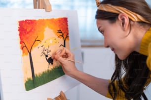 Jovem artista asiática talentosa colorindo na placa de pintura em casa. Atraente bela imagem de arte feminina desenhar, criando obras de arte com tinta aquarela e pincel desfrutar de atividade de criatividade em casa.