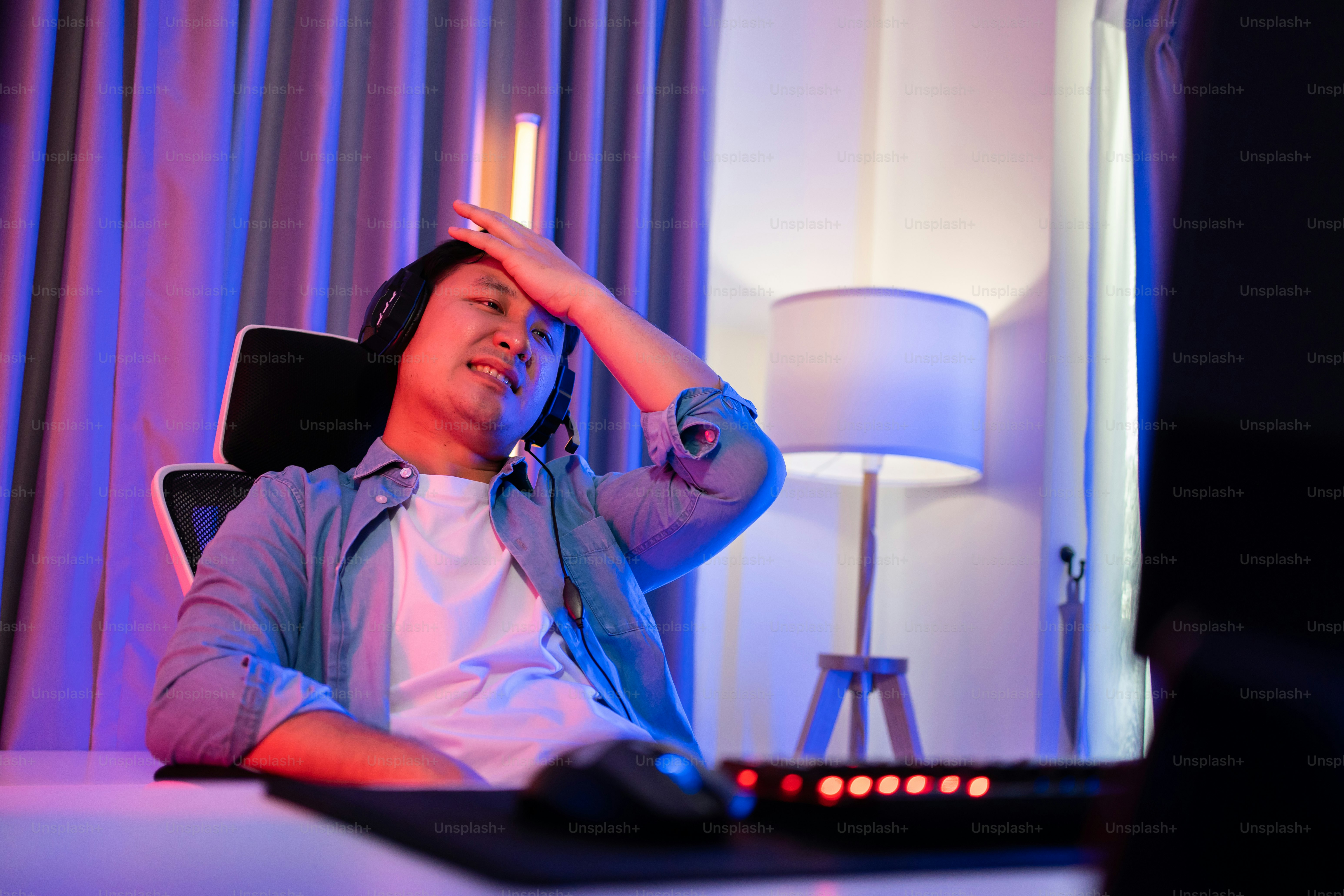 Asian attractive Esport male gamer play online video game on computer. Handsome upset man gaming loser player feel frustrated and angry while broadcast live streaming playing cyber tournament at home.