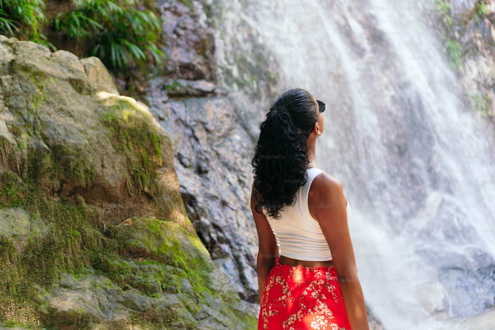熱帯の滝の底にいる女性。休暇のコンセプト