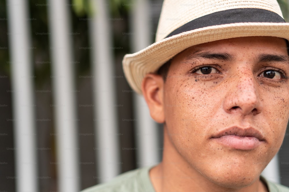 Young man with hat looking at the camera. Man with freckles. Urban life style on the street. Serious look