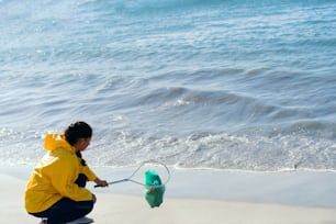 Joven ecologista recogiendo plásticos con una red en la playa