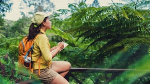 The young woman who is sitting writing, recording and studying the nature of the forest.