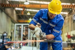 Caucasian handsome male industrial worker work in manufacturing plant. Attractive young man industry factory engineer wear hardhat and protective eyeglass then welding steel at manufactory warehouse.